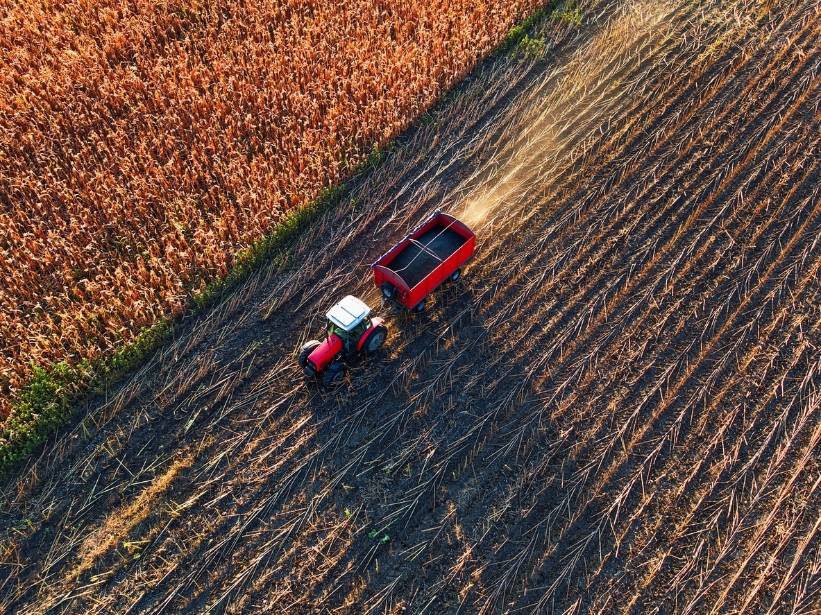 Aerial view of farmer driving agricultural tractor and trailer full of grain